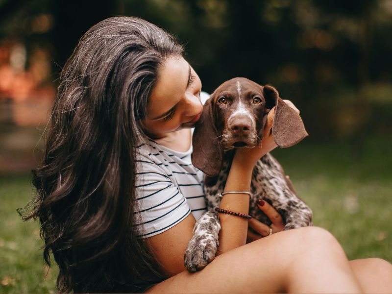 Woman embraces brown puppy